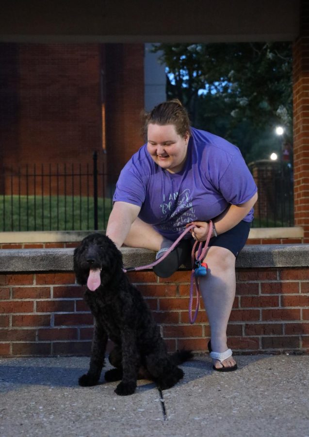 Abigail Turner and her support goldendoodle Daisy take a break on an evening walk on the WKU campus. 